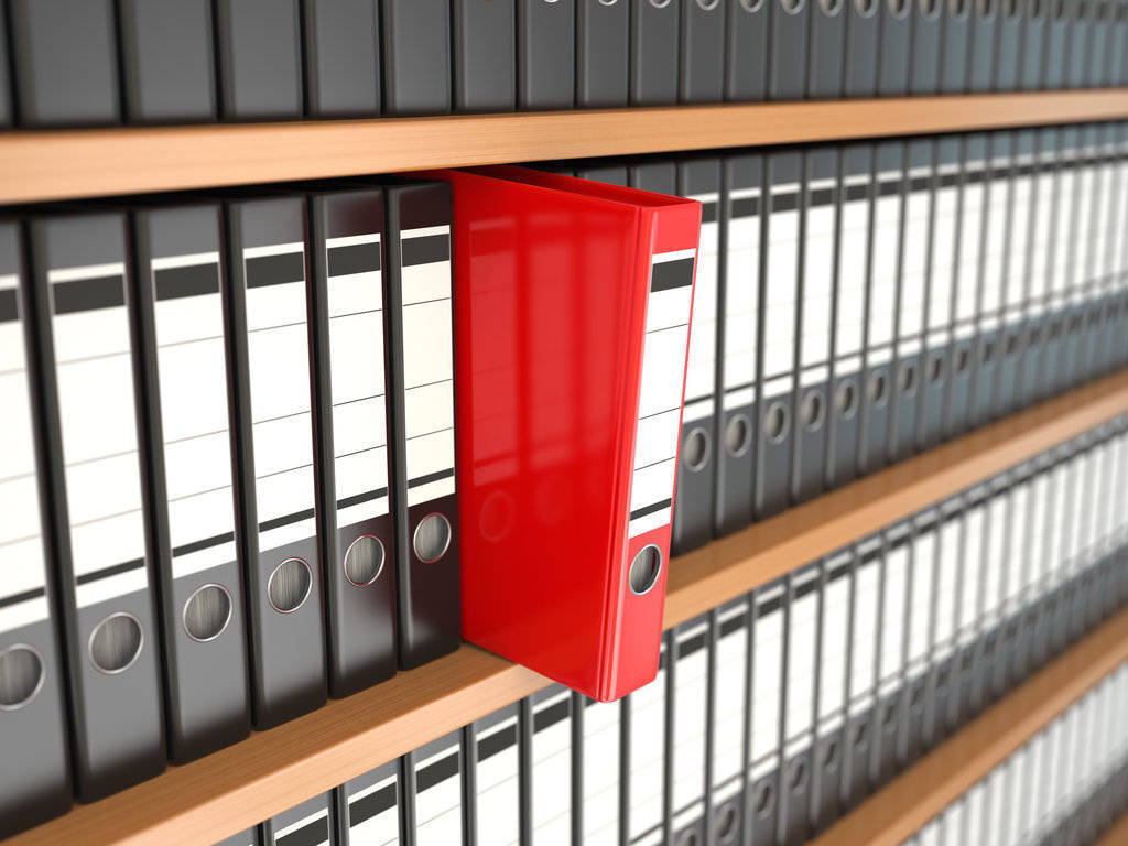 Red file office binder on a shelf full of black office binders