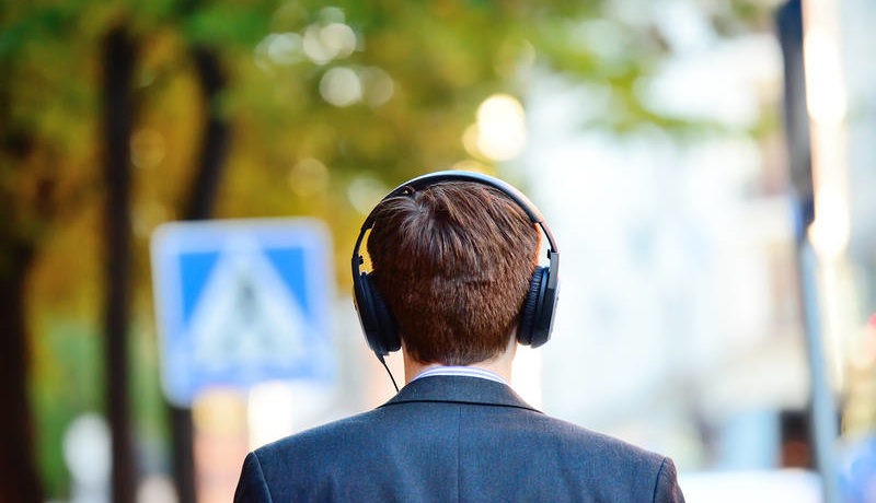 Man in suit listening to a podcast through his headphones
