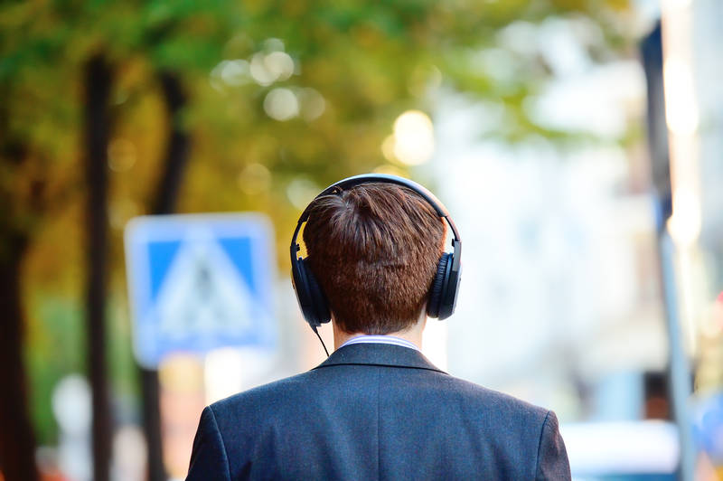 Man in suit listening to a podcast through his headphones